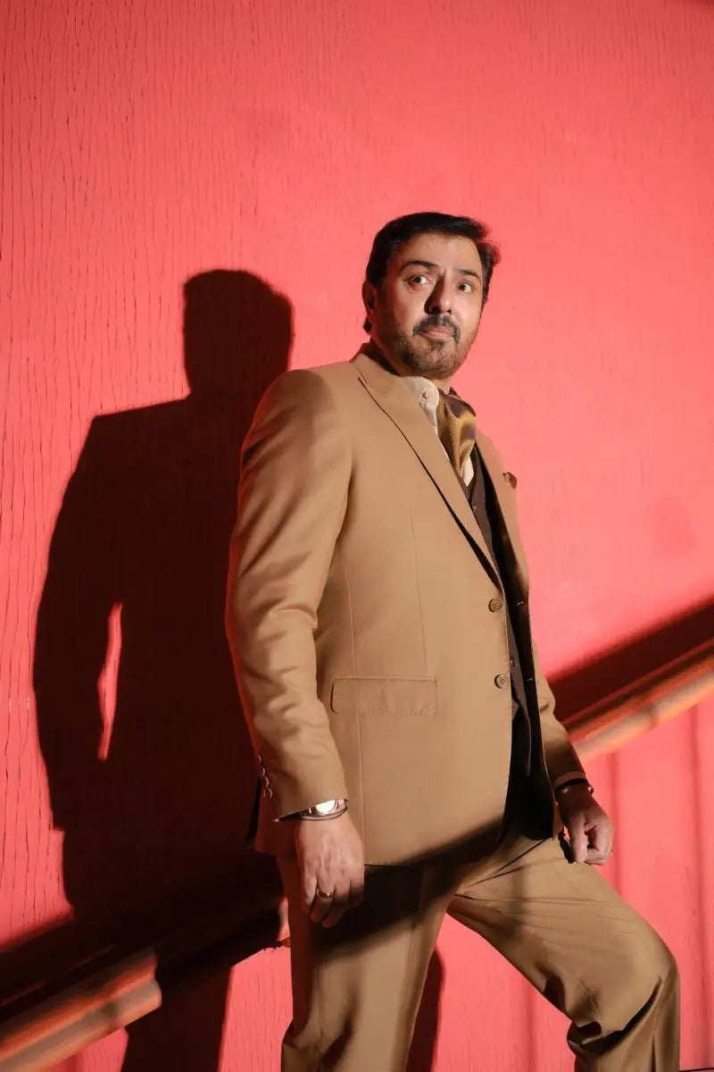 A man wearing a tan designer 3-piece suit with matching tie and dark shirt from agha talish for luxury pakistani groom wear