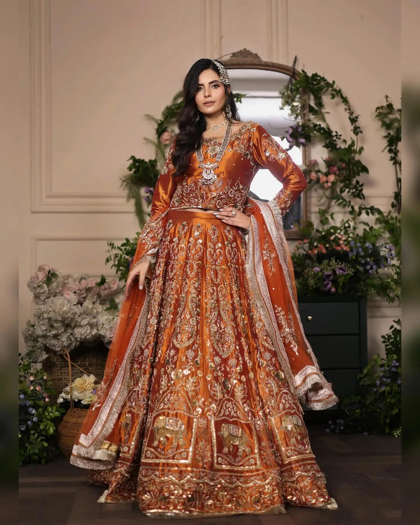 Ornate orange bridal lehenga ambar with intricate gold embroidery and elephant motifs in vibrant amber rust hue