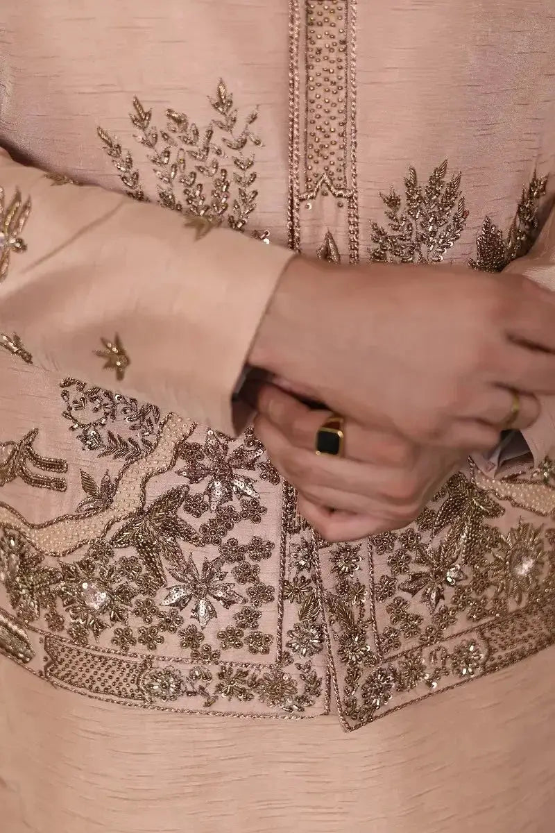A delicate peach-colored raw silk kurta gulzar-e-raunaq with intricate gold thread and sequin embroidery on cuffs and hem