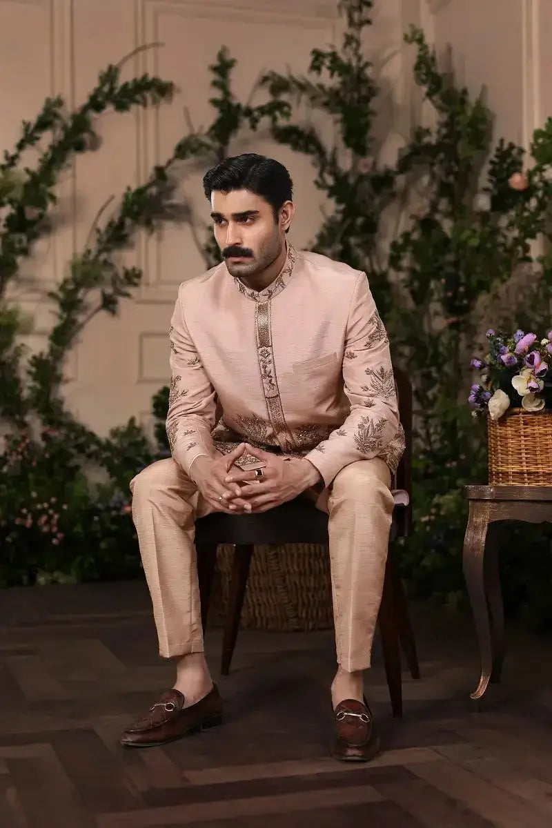 A man wearing a beige raw silk intricately embroidered sherwani with matching trousers and brown leather loafers from Gulzar-e-Raunaq