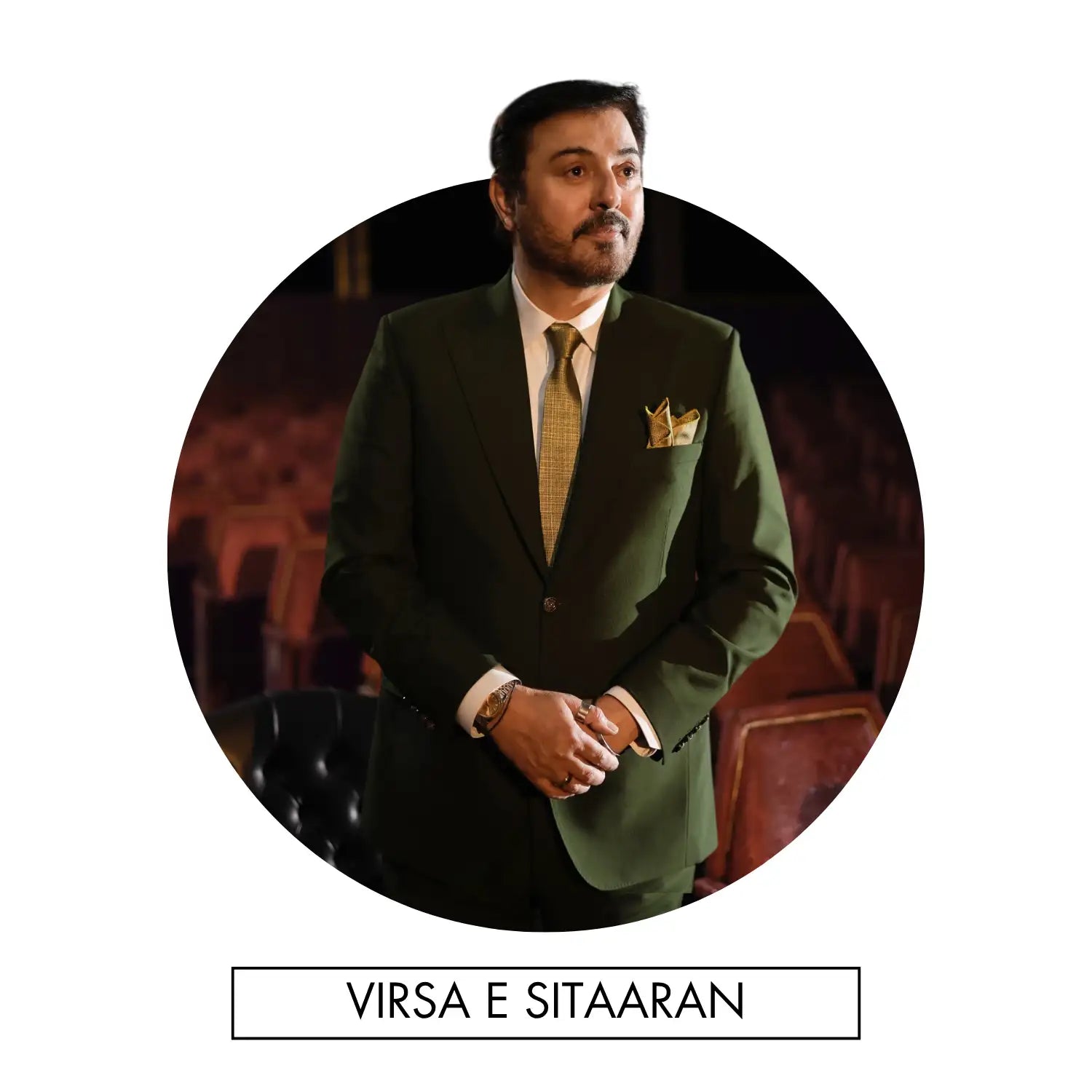 A man in a dark green suit with a gold patterned tie and matching pocket square.