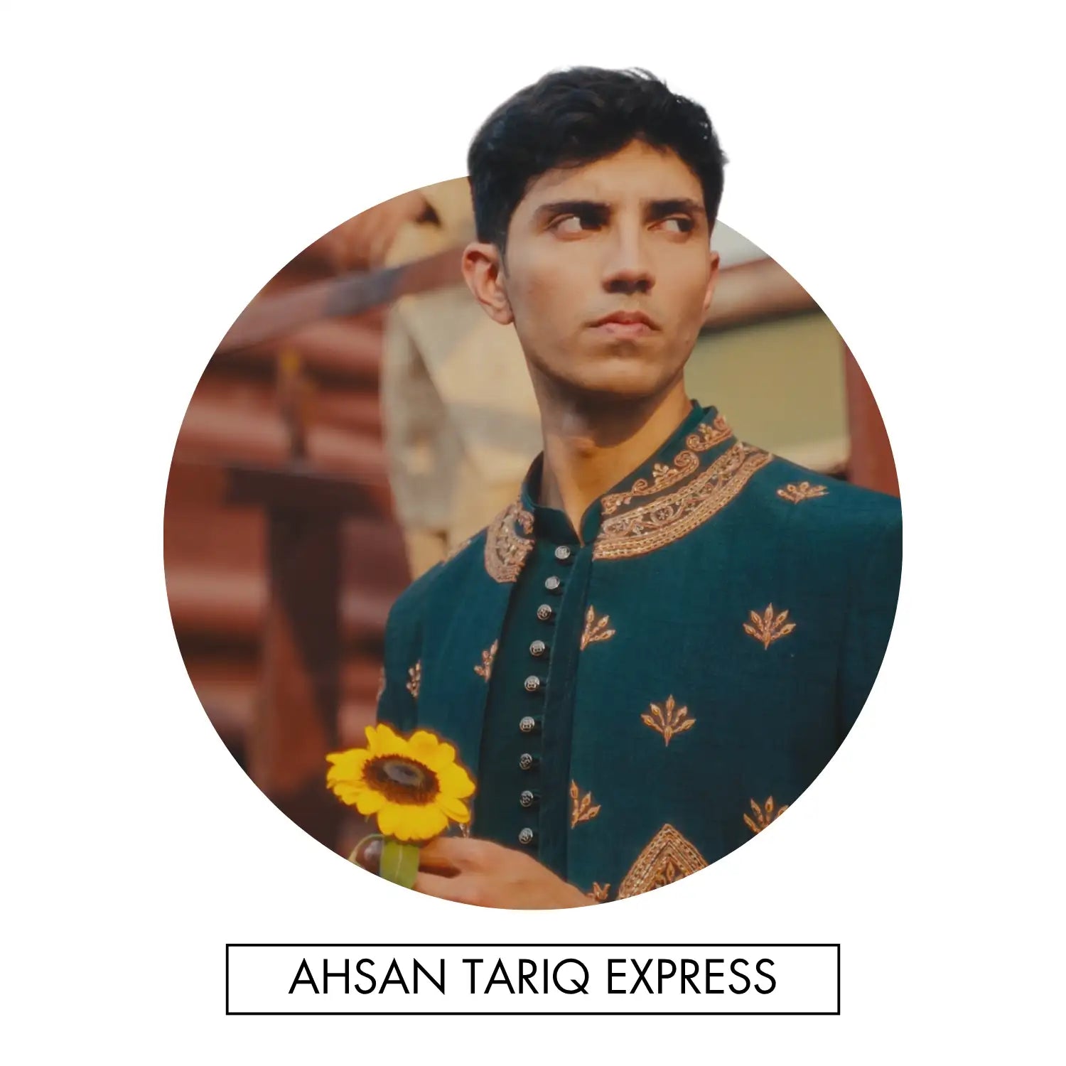 A man in a teal embroidered jacket with gold leaf patterns and silver buttons holds a bright yellow sunflower.