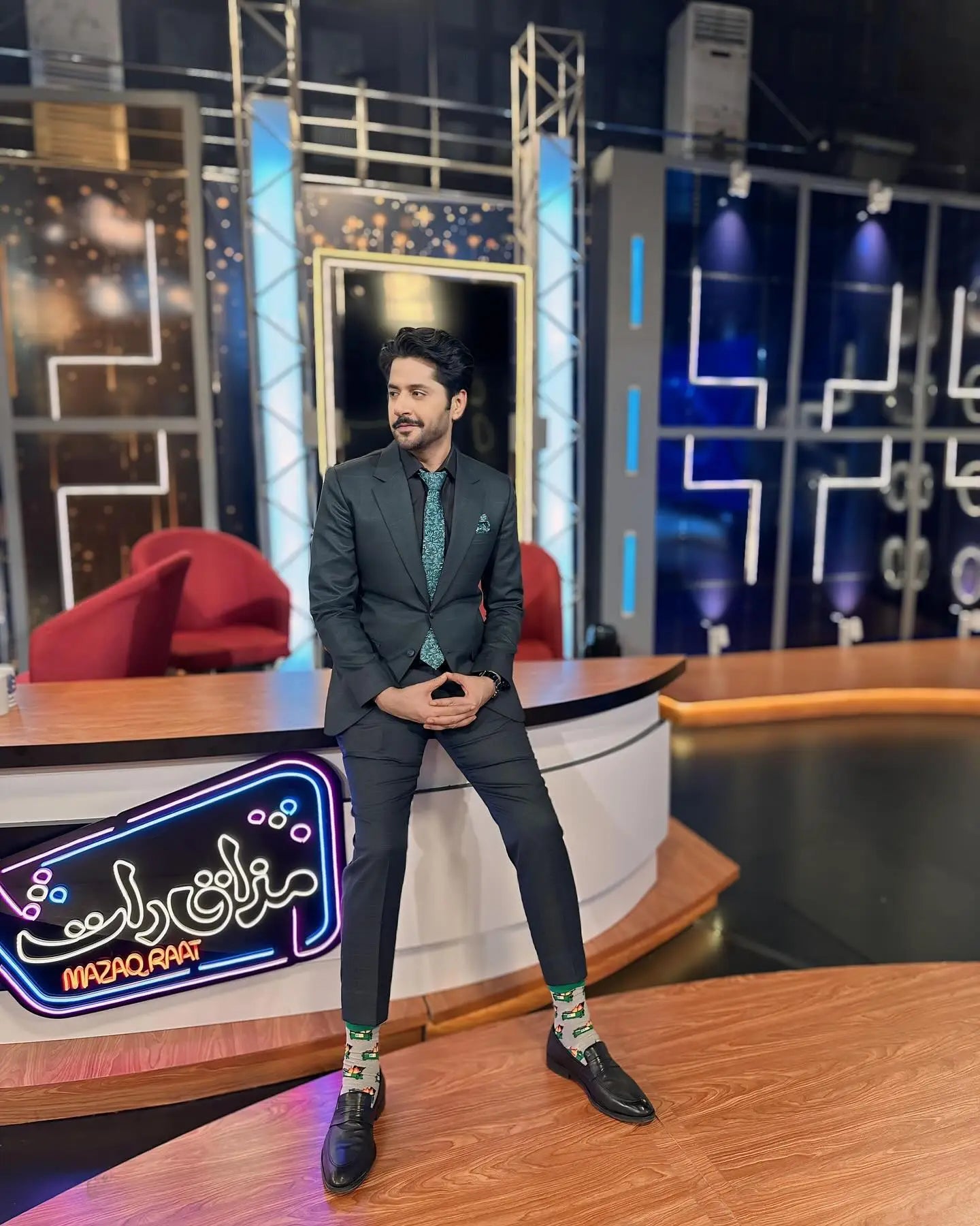 A dark gray suit with subtle sheen paired with teal patterned tie and pocket square in midnight flora by ahsan tariq