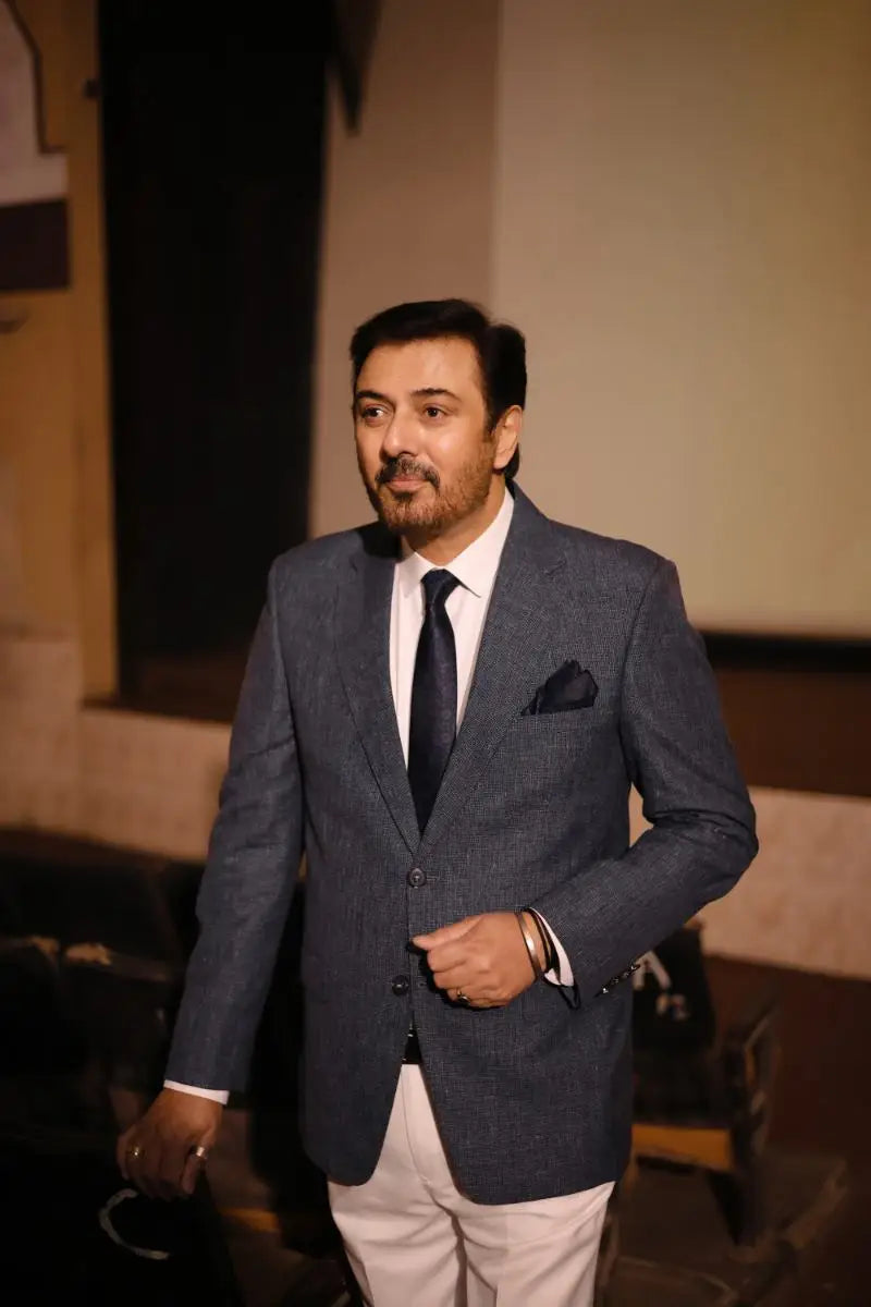 A man wearing a navy blue textured blazer with matching pocket square and white trousers in Muhammad Ali Virsa-e-Sitaaran Edit 26