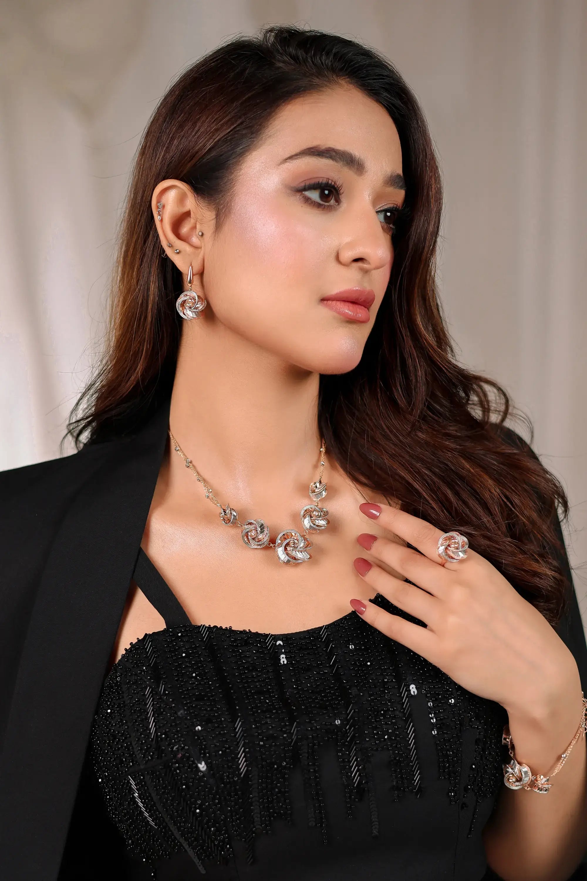 A woman wears a noir éclat rose-themed necklace with clear gemstones set in gold-toned metal by ahsan tariq