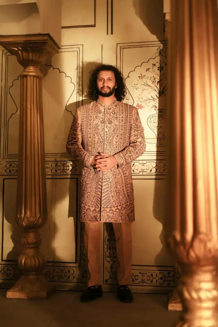 A man wearing a beige and gold embroidered sherwani with intricate patterns from the Qalandar collection