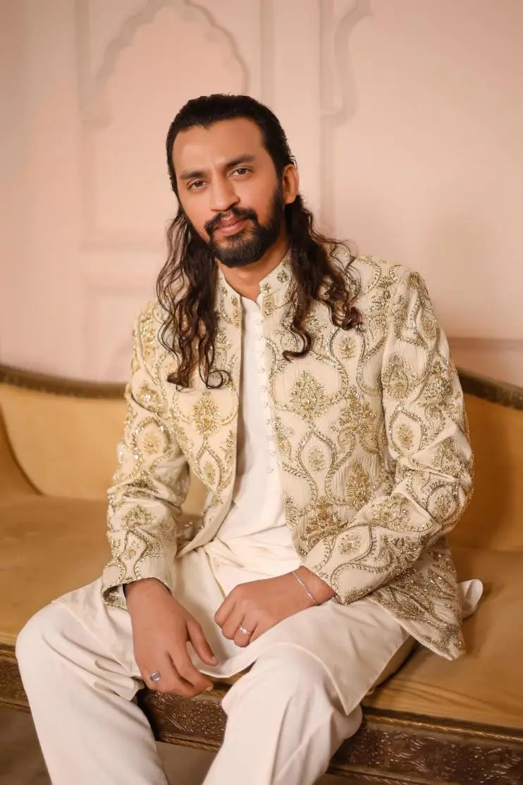 Cream-colored sikandar jacket with intricate gold thread embroidery highlighting its luxurious design