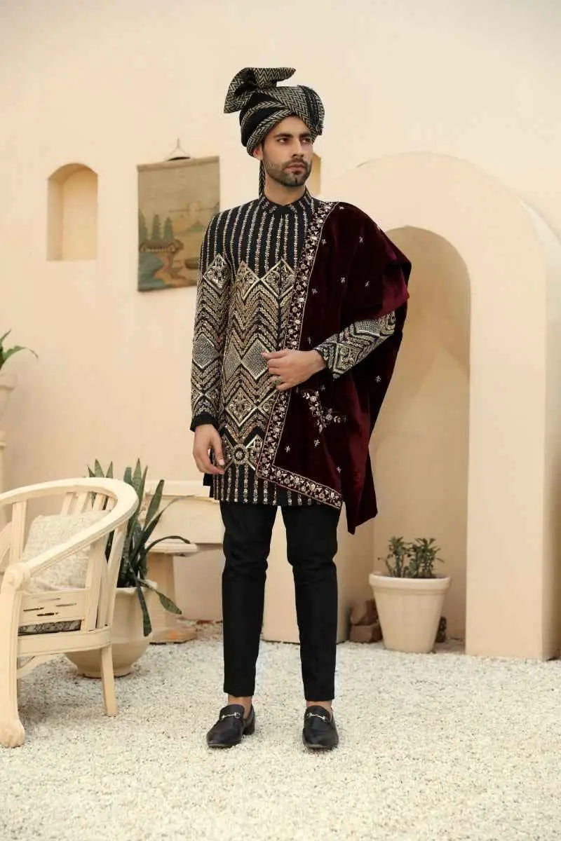A man wearing a siyah nishaan kurta with black and gold embroidery paired with a maroon velvet stole from raqeeb se collection