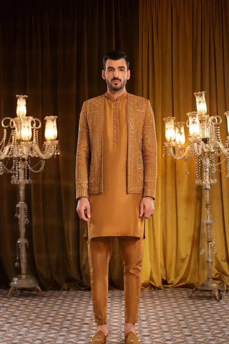 A man wearing a taimoor gold raw silk suit with heavy embellished work featuring a traditional jacket and matching pants