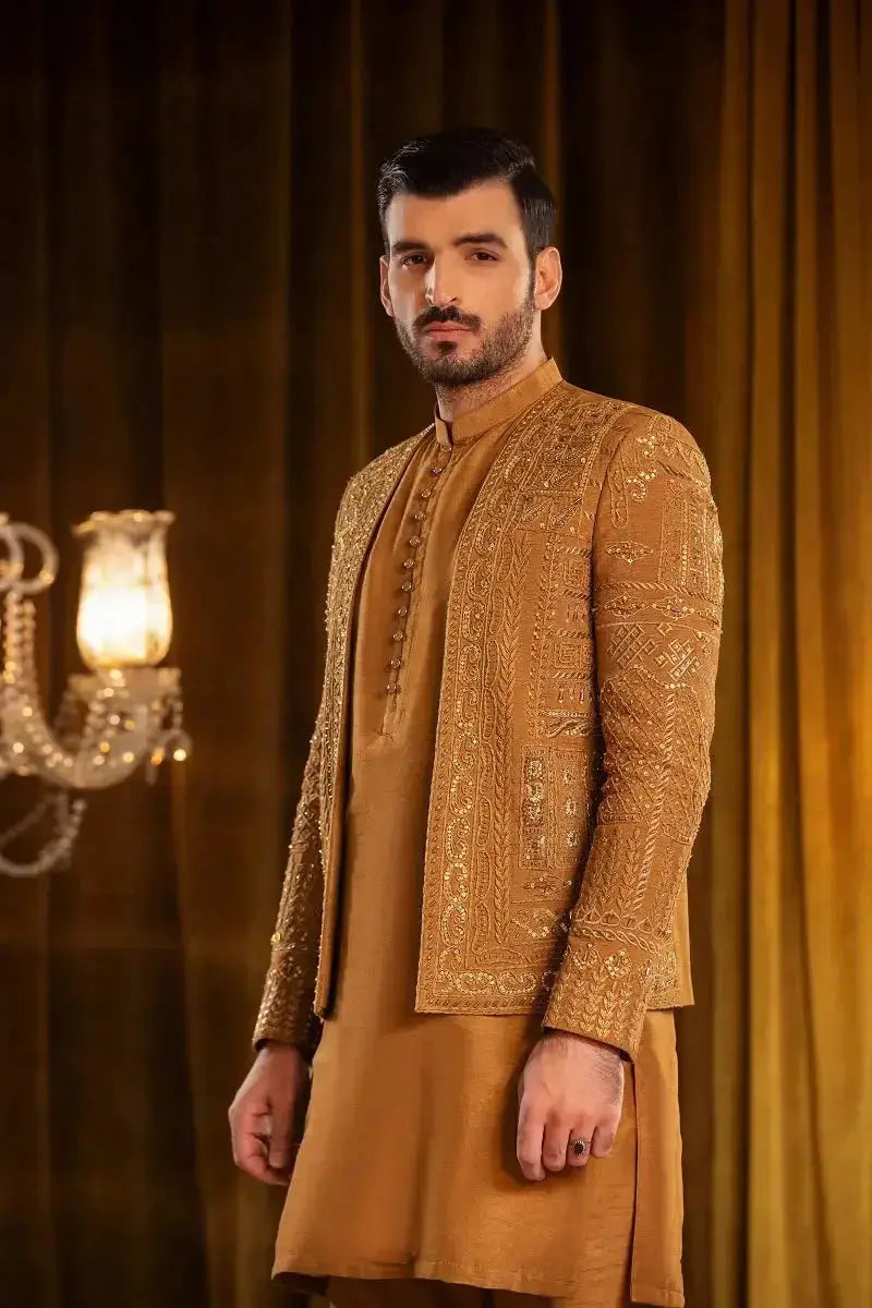 A man wears a gold raw silk suit taimoor with heavy embellished work and intricate embroidery patterns