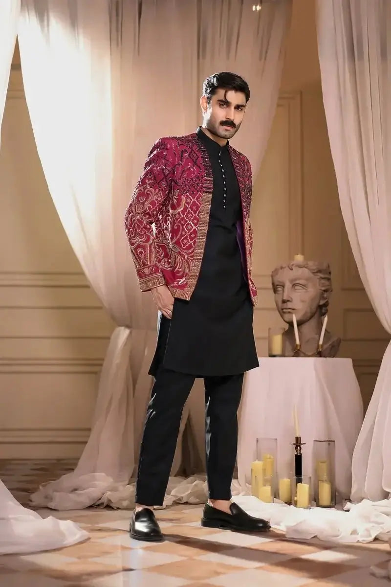 A man wearing a thakur singh magenta and gold embroidered jacket over black formal wear