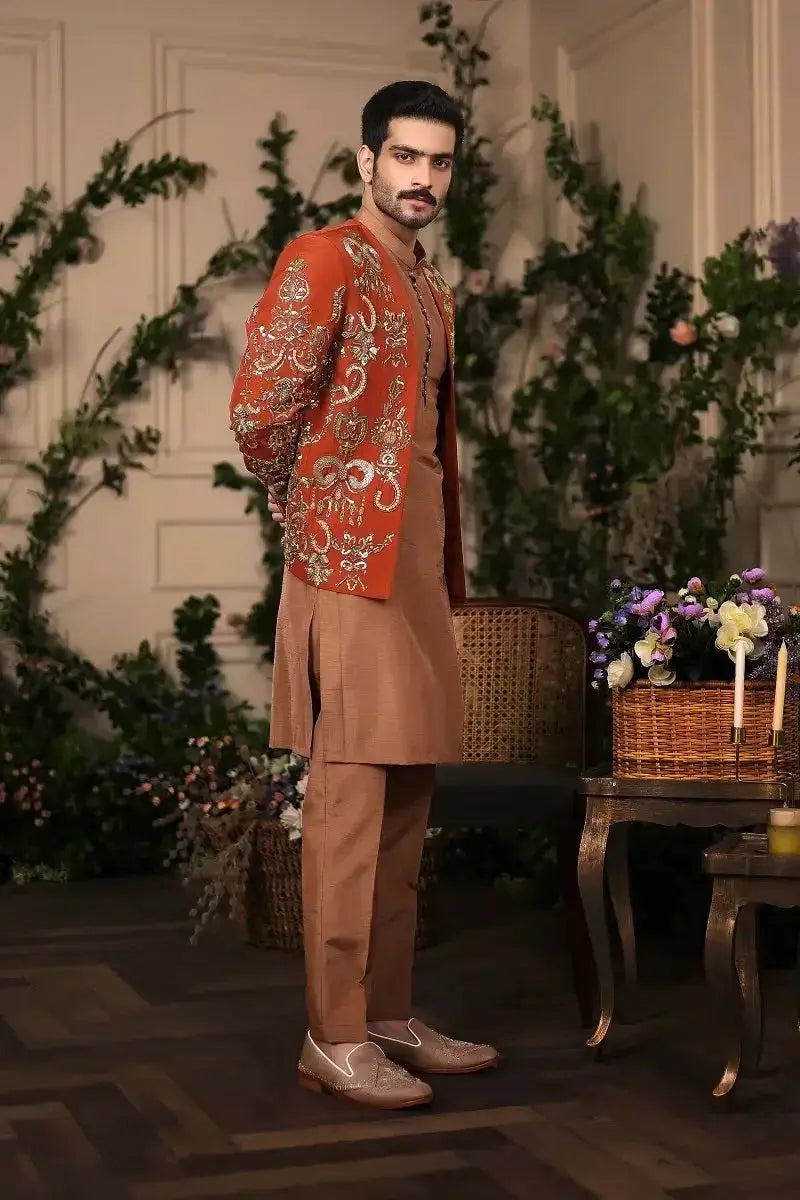 The Wazir Khan jacket is a vibrant orange embroidered garment with intricate gold threadwork paired with tan trousers