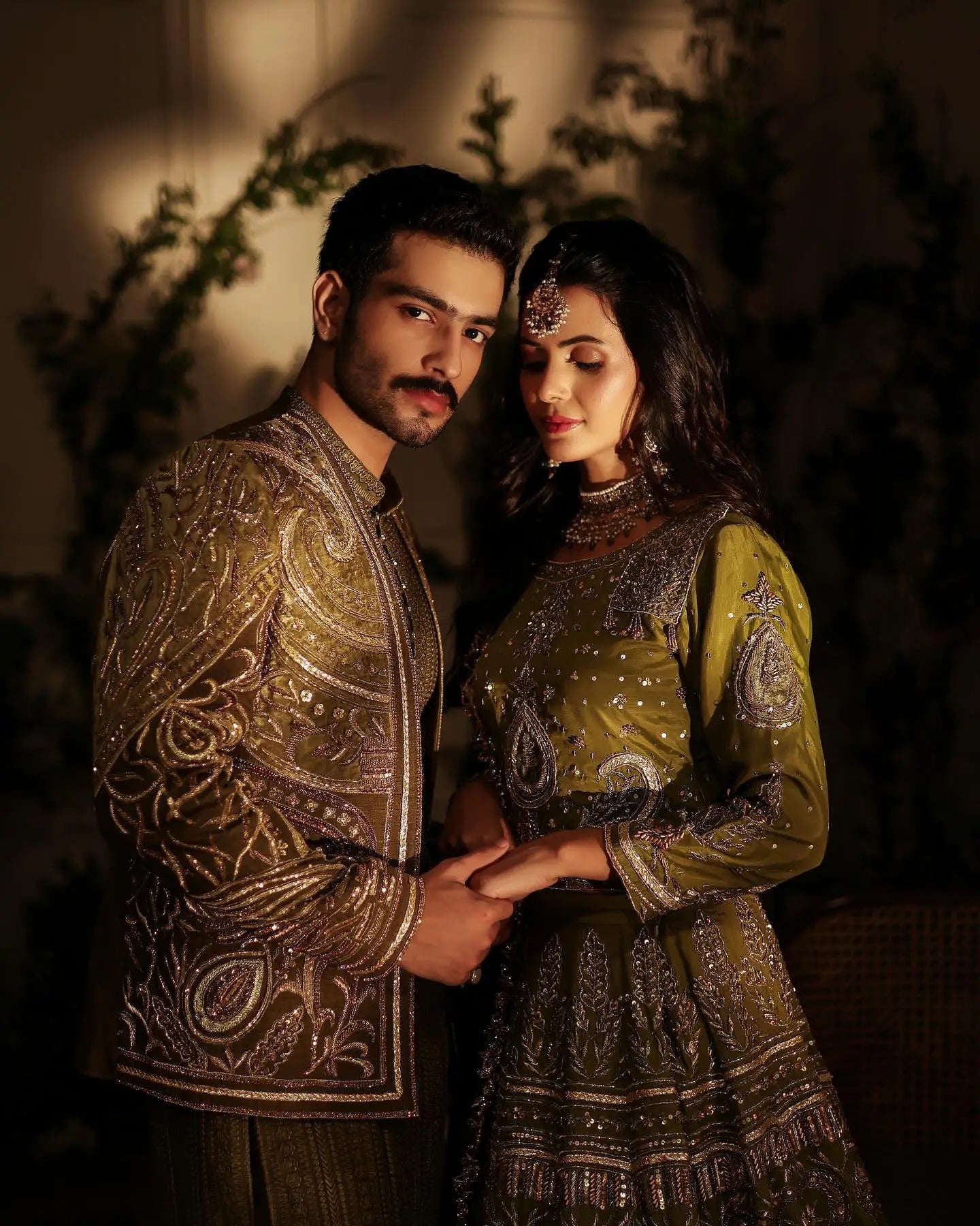 The couple wears ornate olive-green traditional indian attire with antique gold embroidery from ahsan tariq zebaish collection