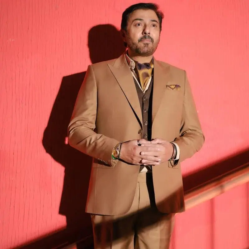 A man wearing a tan designer 3-piece suit with patterned tie and pocket square for luxury pakistani groom wear