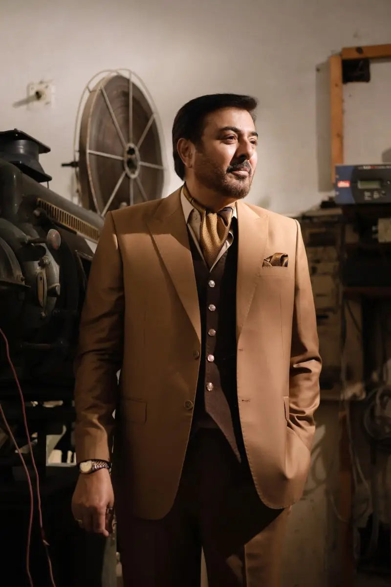 A man wearing a luxury pakistani groom wear tan 3-piece suit with matching vest and dark brown waistcoat by agha talish