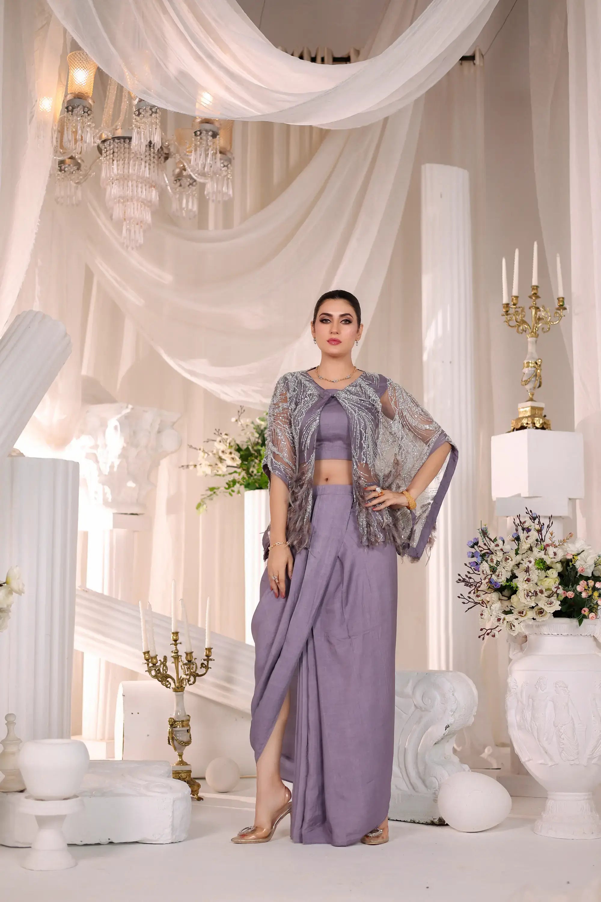 A woman wearing a lavender flowing two-piece amara drape ensemble with an embellished sheer capelet