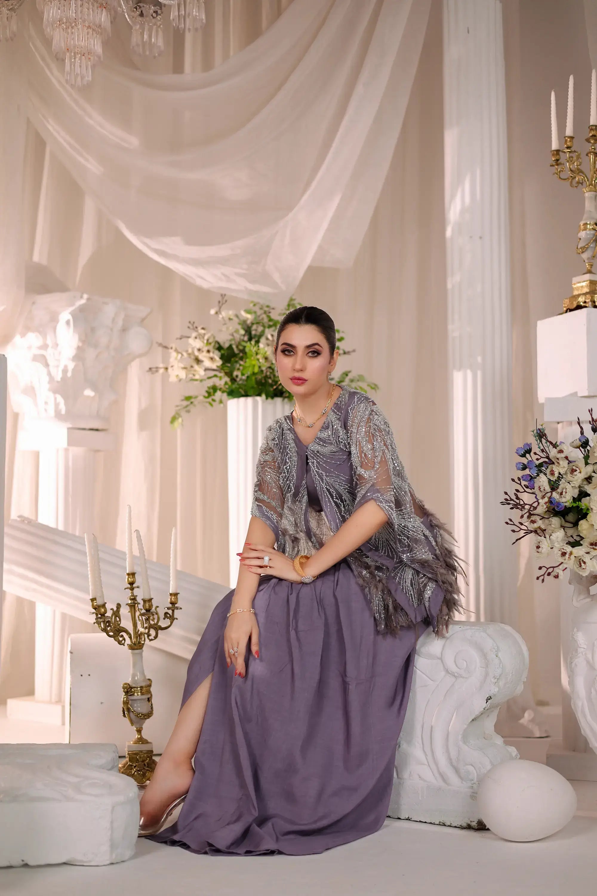 A woman wears a lavender satin gown with a silver sequin embellished sheer capelet in the amara drape ensemble