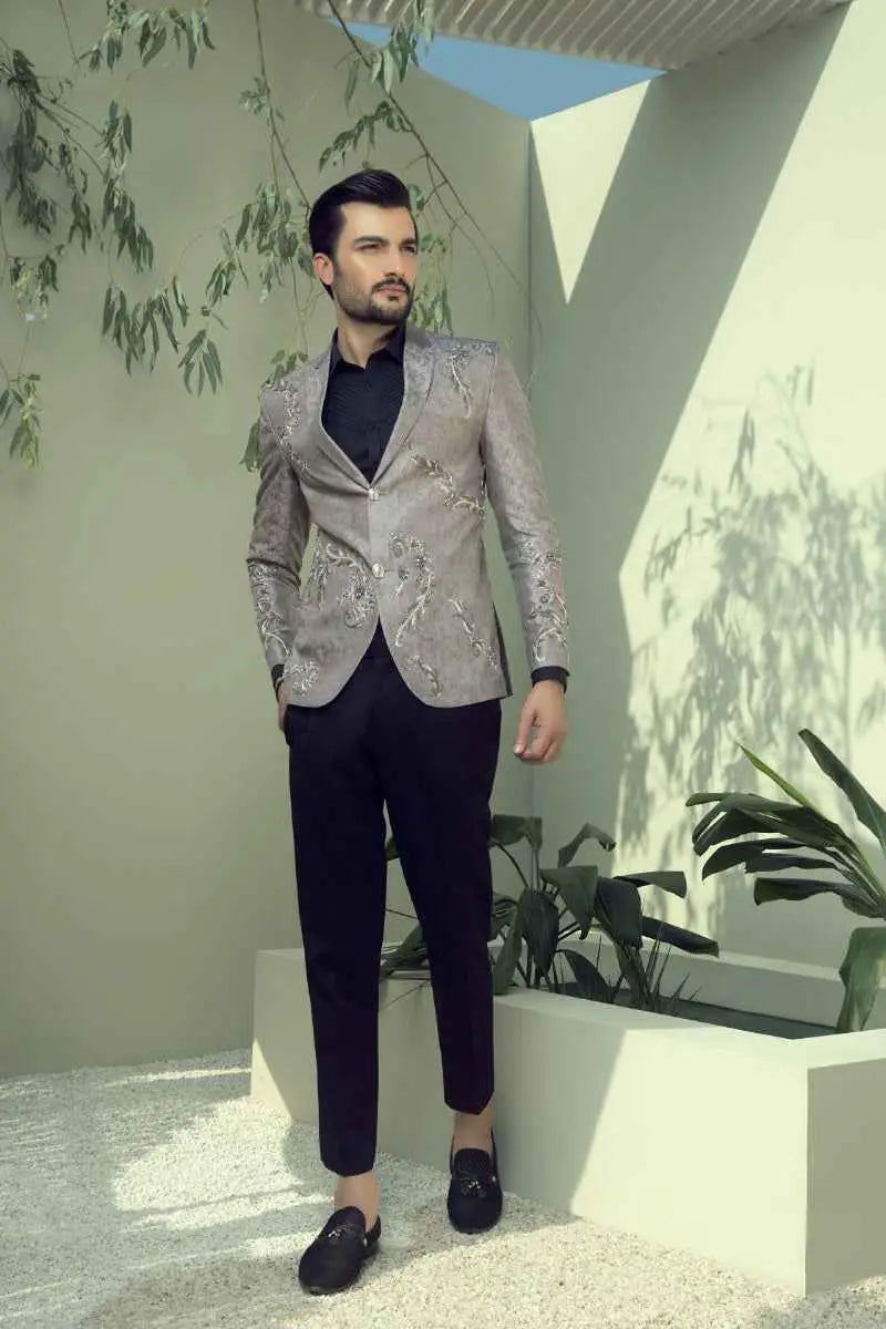 A man wearing a distinctive slate-grey textured Argentum blazer with gold embroidery and black trousers and loafers