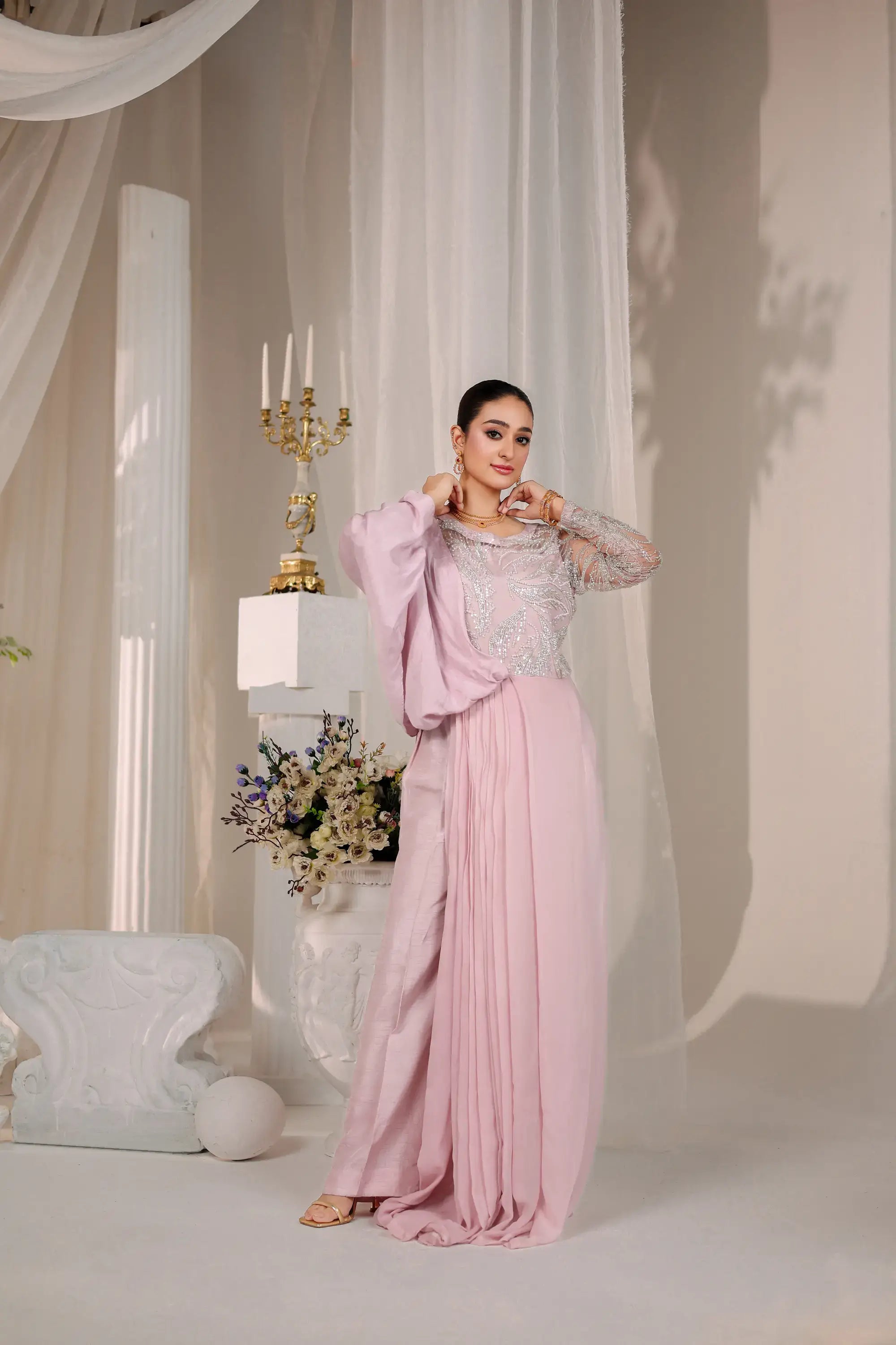 A flowing blush opulence gown by ahsan tariq in soft blush pink with a sheer embellished bodice and long sleeves