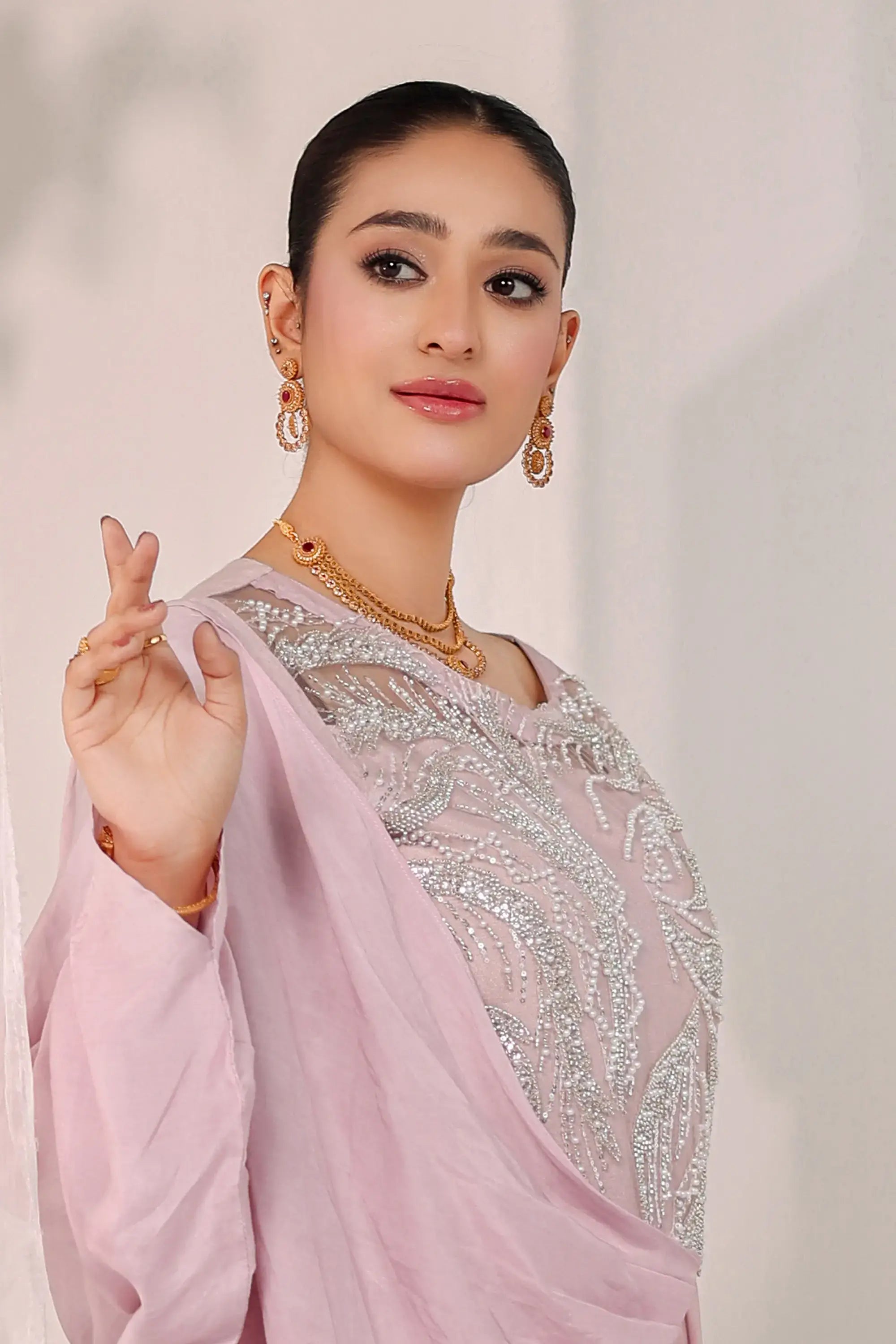 A woman wears a blush opulence saree by ahsan tariq in soft blush pink with intricate silver embroidery on the bodice