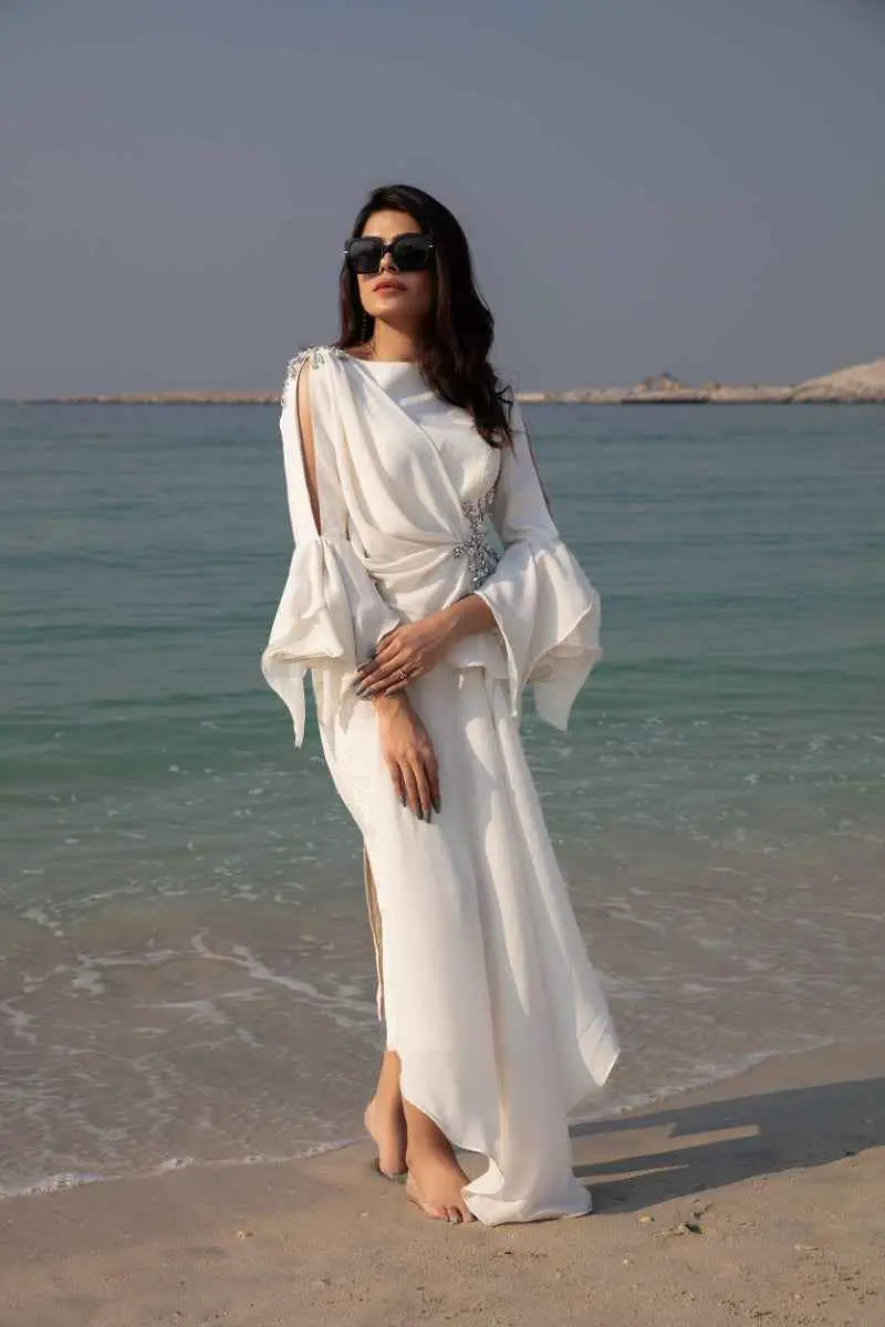 A flowing white gown with bell sleeves and draped asymmetrical design featuring celestial drape high-fashion statement piece