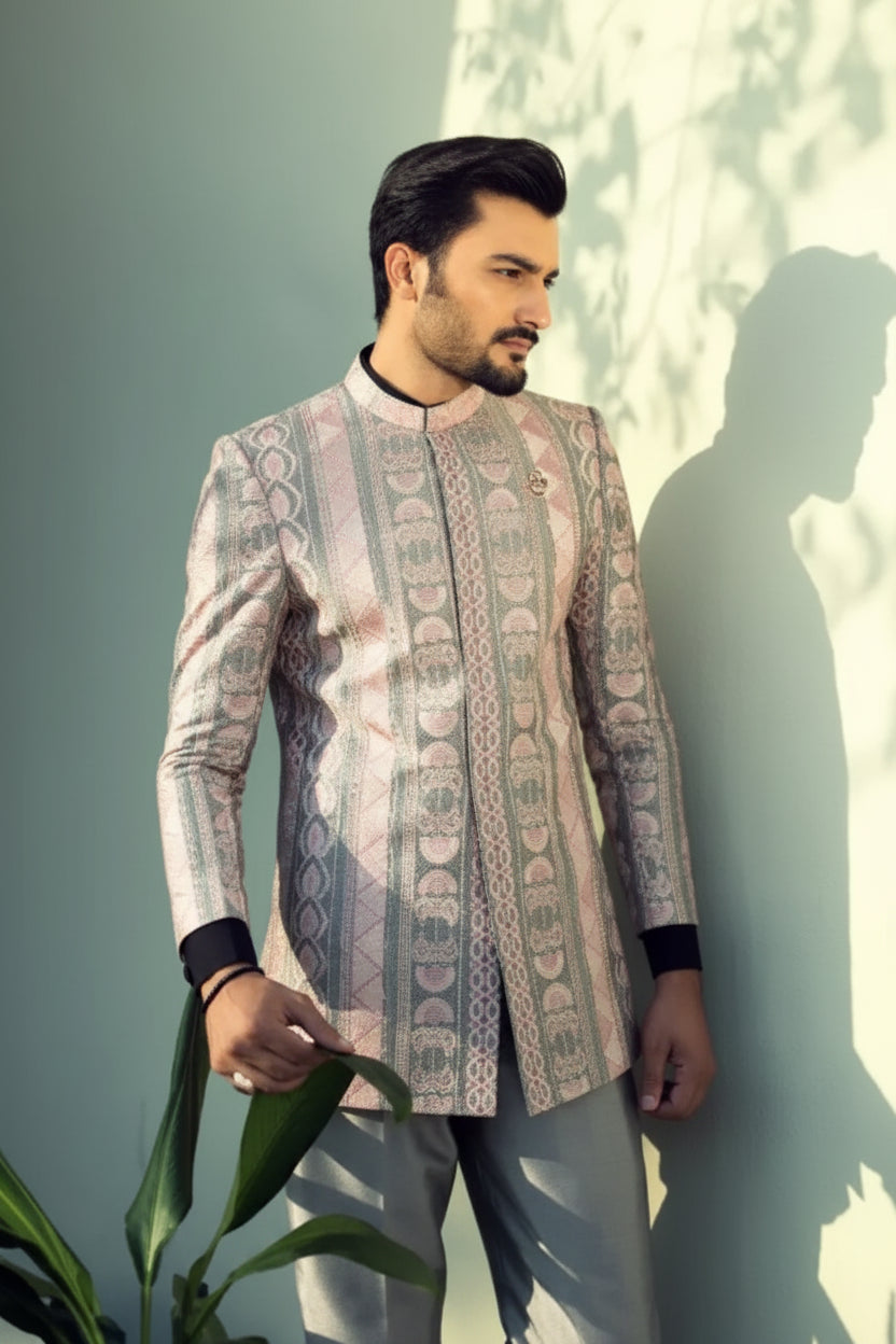 A man wearing a light beige intricately patterned traditional jacket with black cuffs and collar in chrome by ahsan tariq