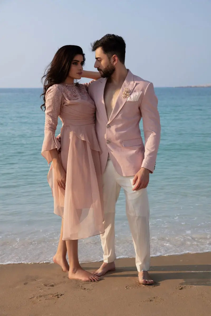 The dusk duo features a couple in matching blush pink formal attire by ahsan tariq with a flowing dress and tailored blazer
