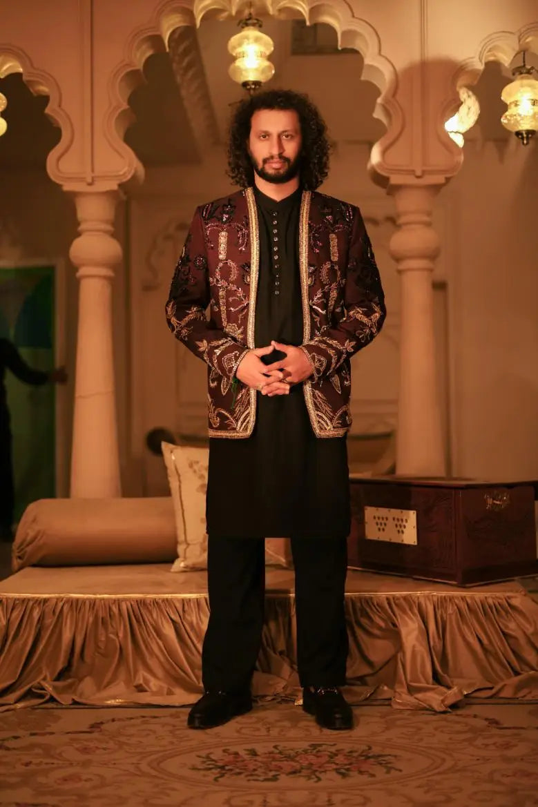 The man wears a ghazi maroon and gold patterned jacket with intricate embroidery and detailed edges