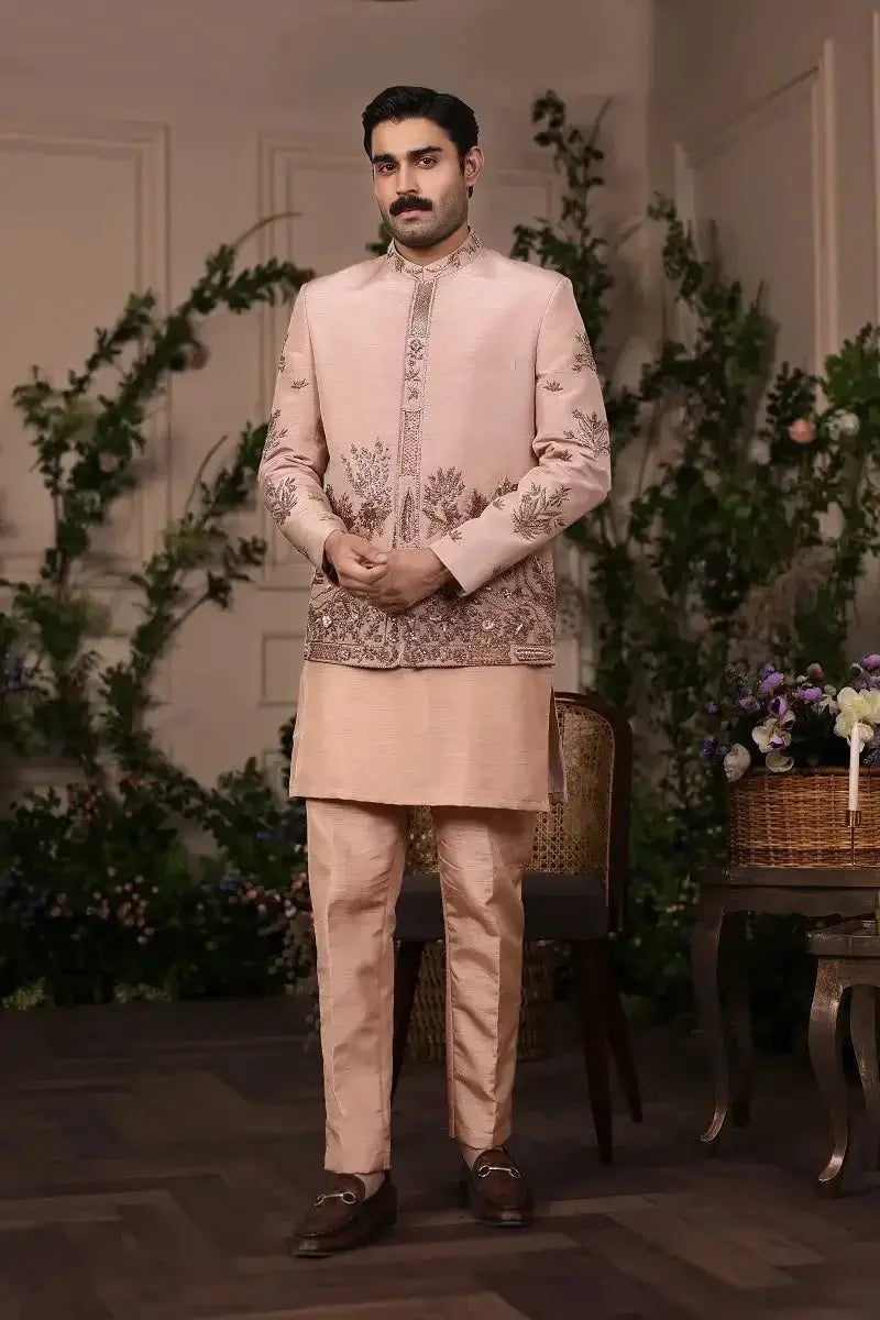 A man wearing a blush pink raw silk sherwani gulzar-e-raunaq with gold thread embroidery on front and sleeves