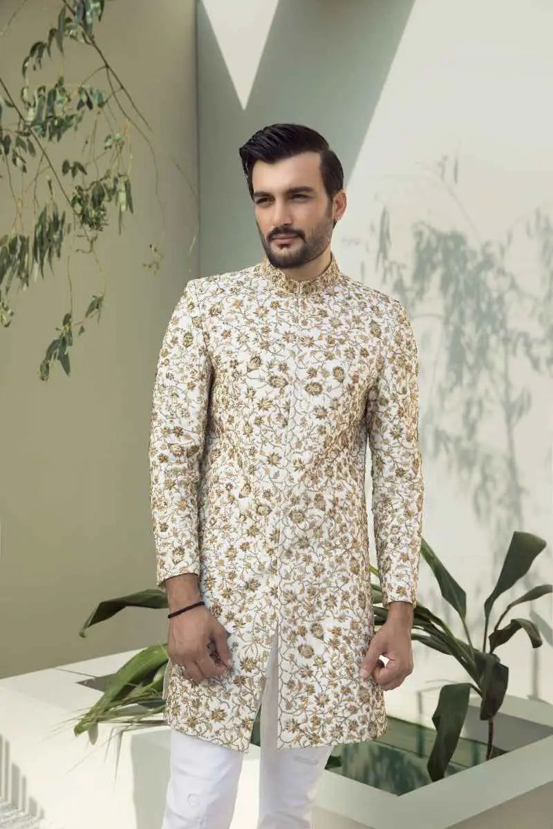 A man wearing an ivory aura cream sherwani with intricate gold floral embroidery classic ivory meets royal elegance