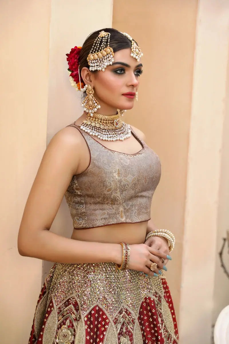 The Malika lehenga skirt features an ornate red and metallic gold pattern with antique gold tilla embellishments