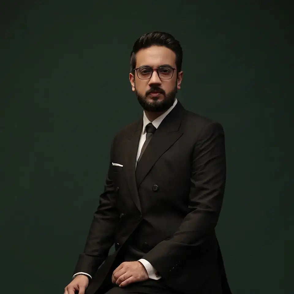 A man wearing a black double-breasted suit with a white shirt and dark tie.
