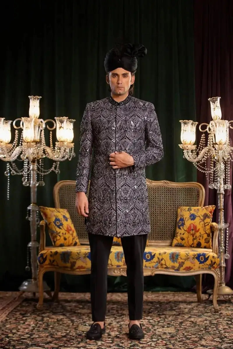 A man wearing a dark gray and black patterned mastaan sherwani with intricate embroidery in raw silk fabric