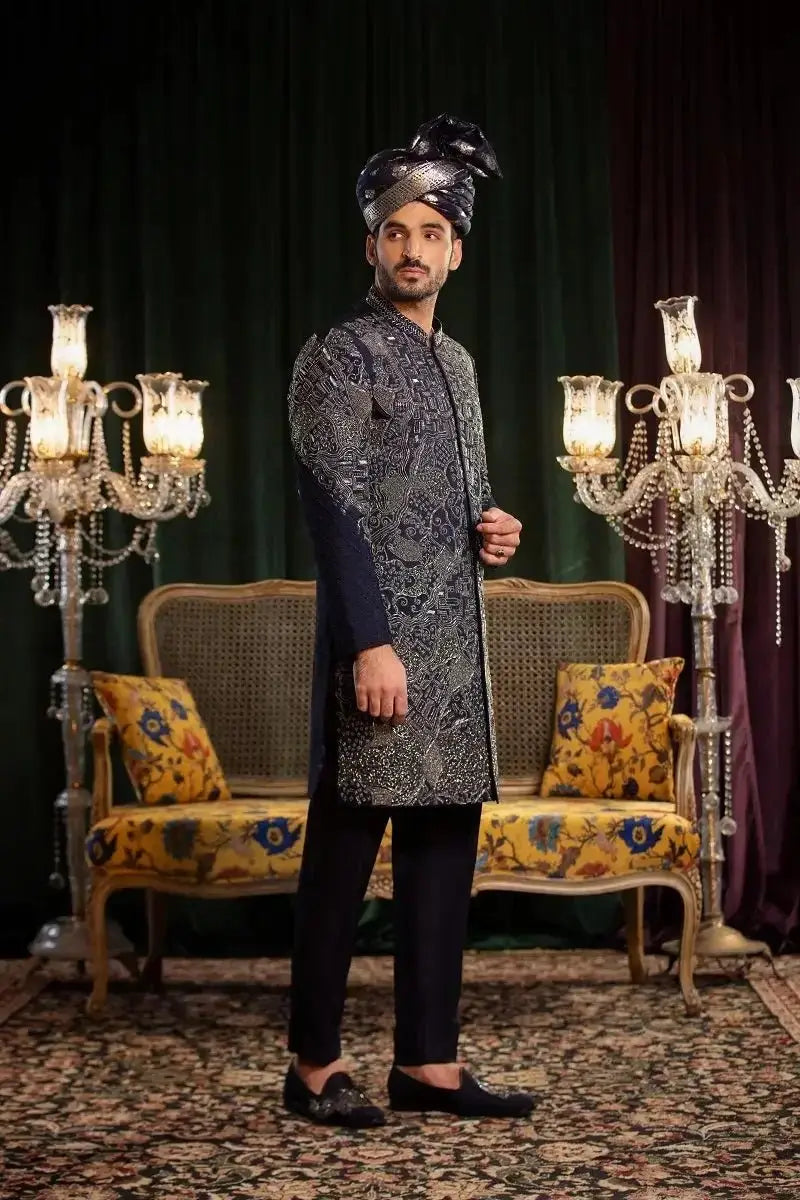 A man wearing mastaan raw silk dark navy sherwani with silver embroidered paisley patterns and matching black trousers