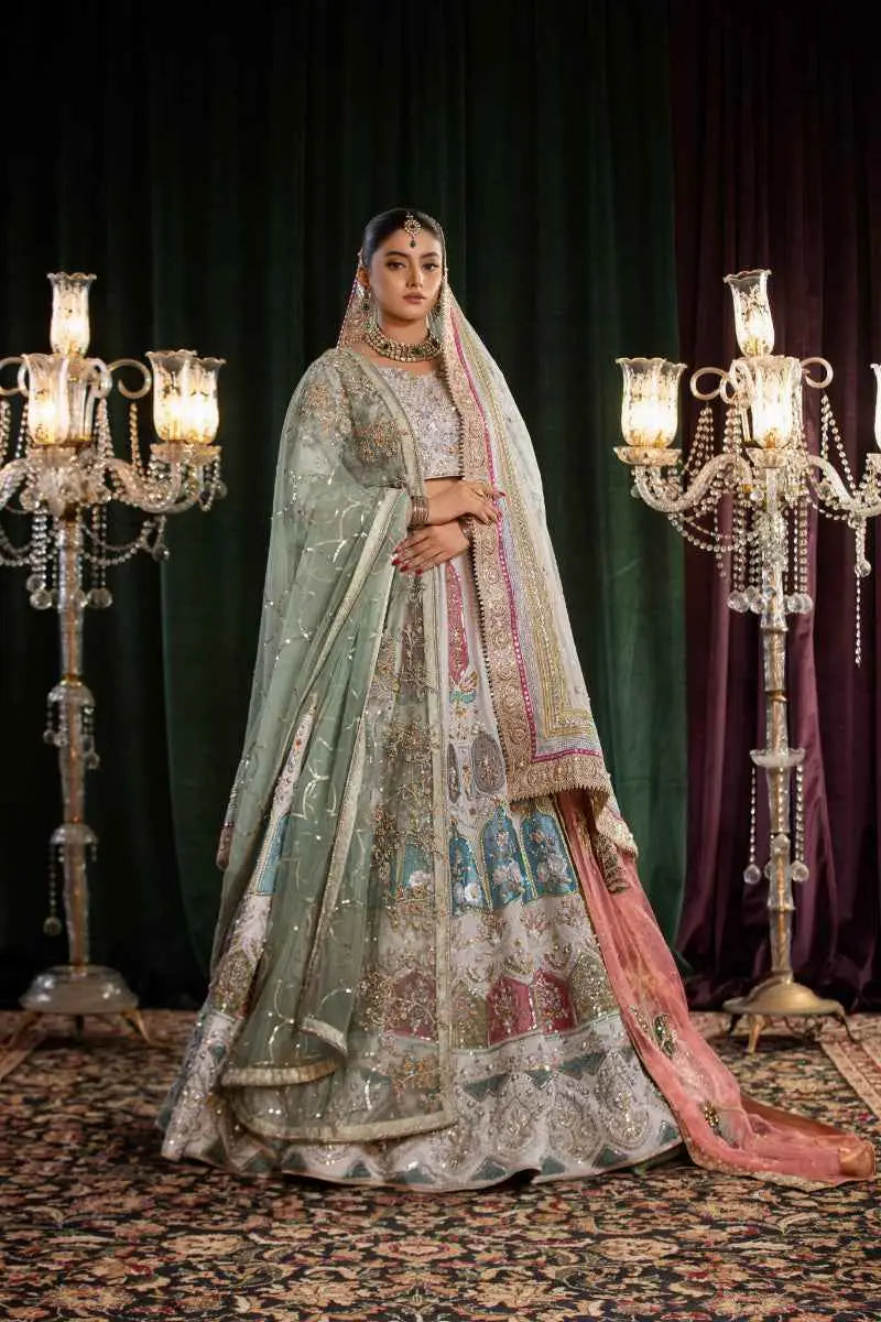 A woman wears a mehr-un-nisa ensemble bridal lehenga in light green and pink with intricate gold embroidery and high-fashion aesthetic