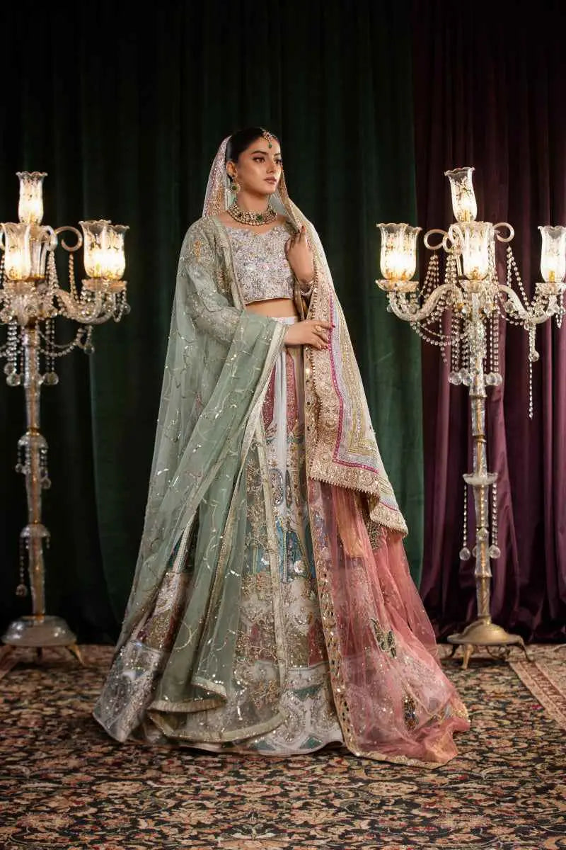 A woman wears the mehr-un-nisa ensemble featuring an ornate light green and pink embroidered lehenga with gold detailing