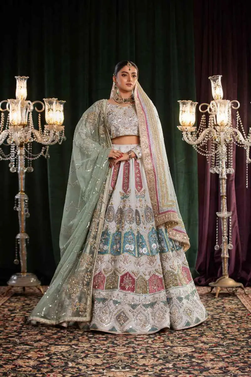 A woman wearing a mehr-un-nisa ensemble soft powder blue lehenga with silver embroidery and gold detailing high-fashion aesthetic