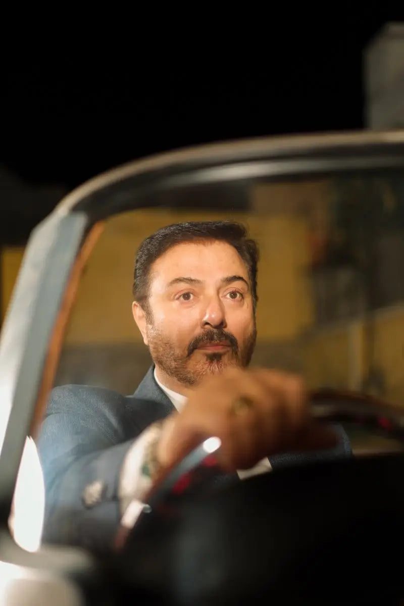 A man with a mustache and beard wearing a dark blue suit jacket and white shirt in Muhammad Ali Virsa-e-Sitaaran Edit 26