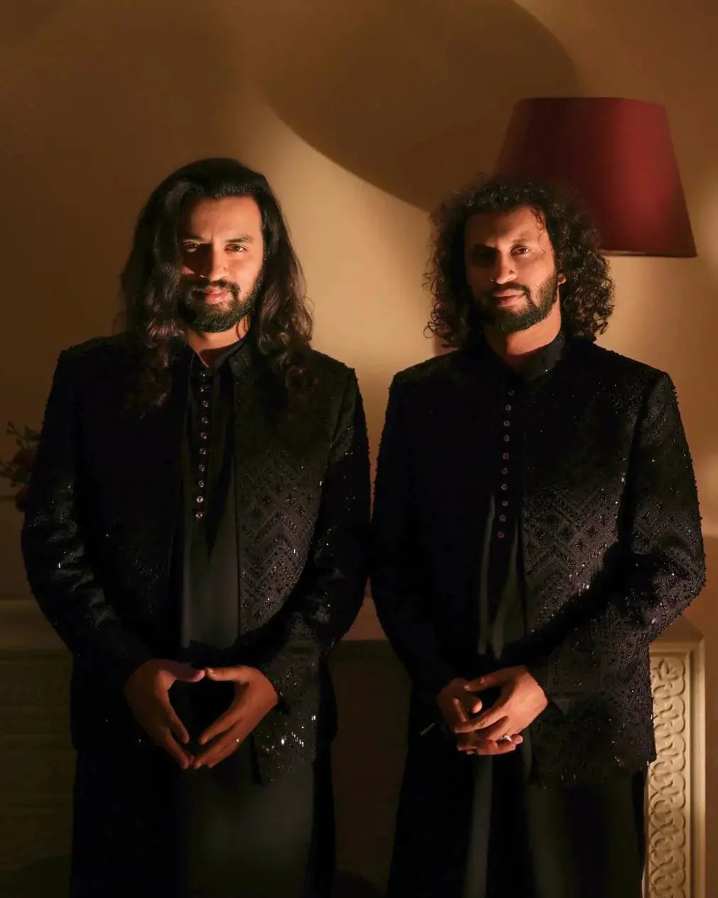 Two men wearing nawab black sequined buttoned jackets standing side by side in matching outfits