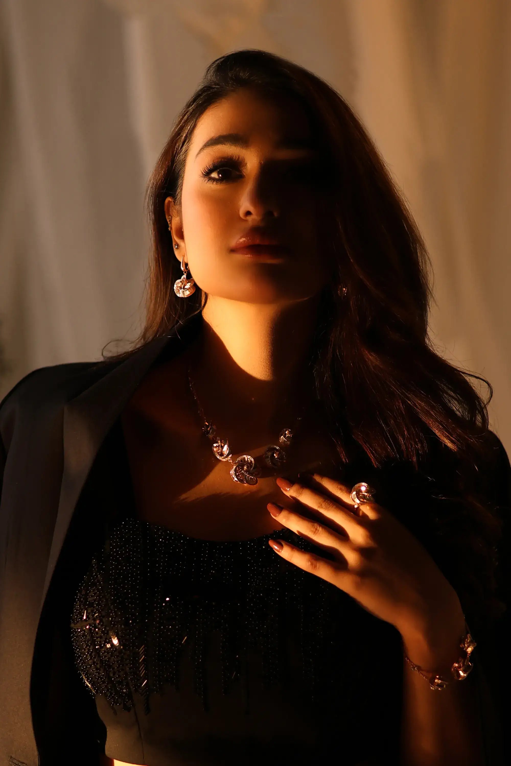 A woman wearing a sleek black sequined top and a silver necklace with gemstone pendants from noir éclat by ahsan tariq