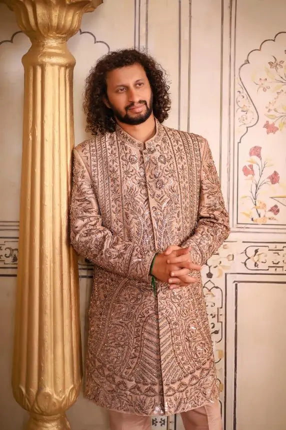 A man wearing a beige and gold embroidered sherwani with intricate paisley patterns from Qalandar collection