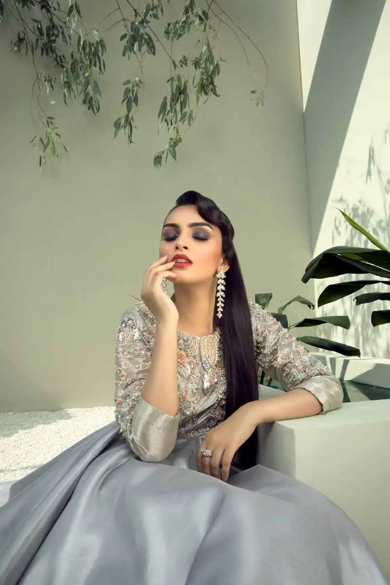 A woman wears a mesmerizing blend ahsan tariq silver gray gown with intricate beading and flowing satin skirt called quicksilver