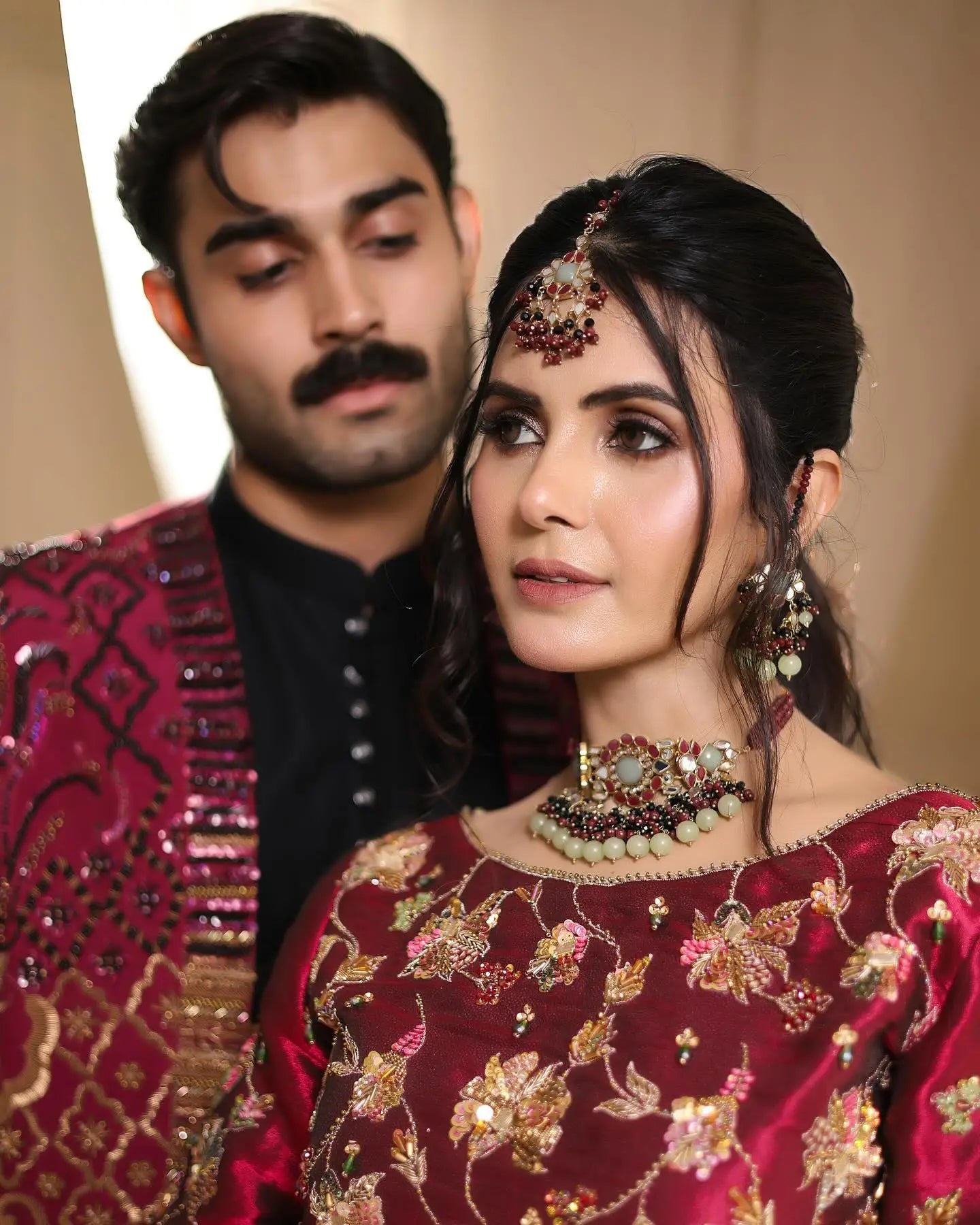 A rich maroon silk bridal gown with intricate gold and pink floral embroidery from the romance fall winter collection