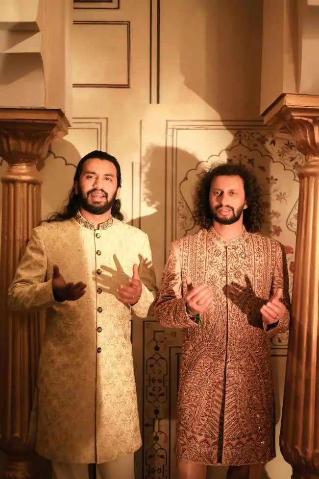 Two men wearing ornate embroidered sherwanis with intricate gold and beige patterns in ranjha design