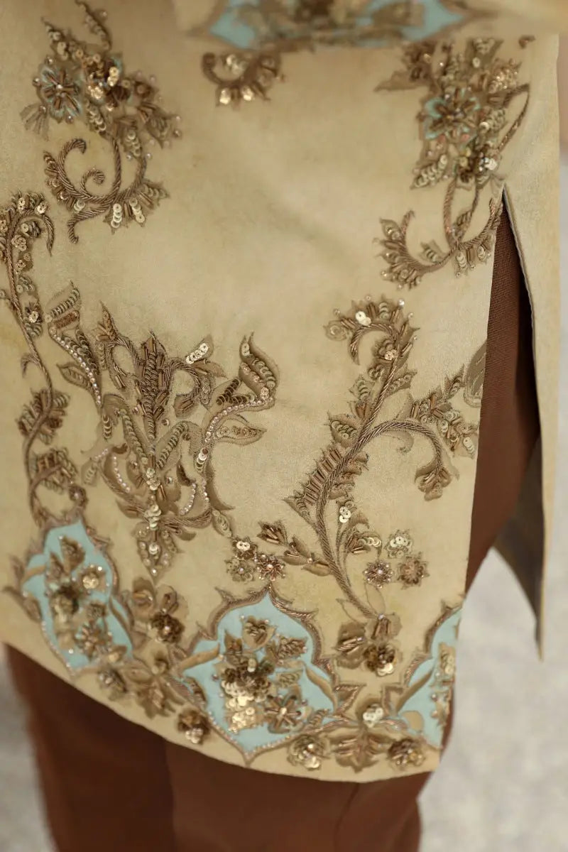 Beige sahar prince coat embroidered with intricate antique gold and light blue floral patterns from raqeeb se collection