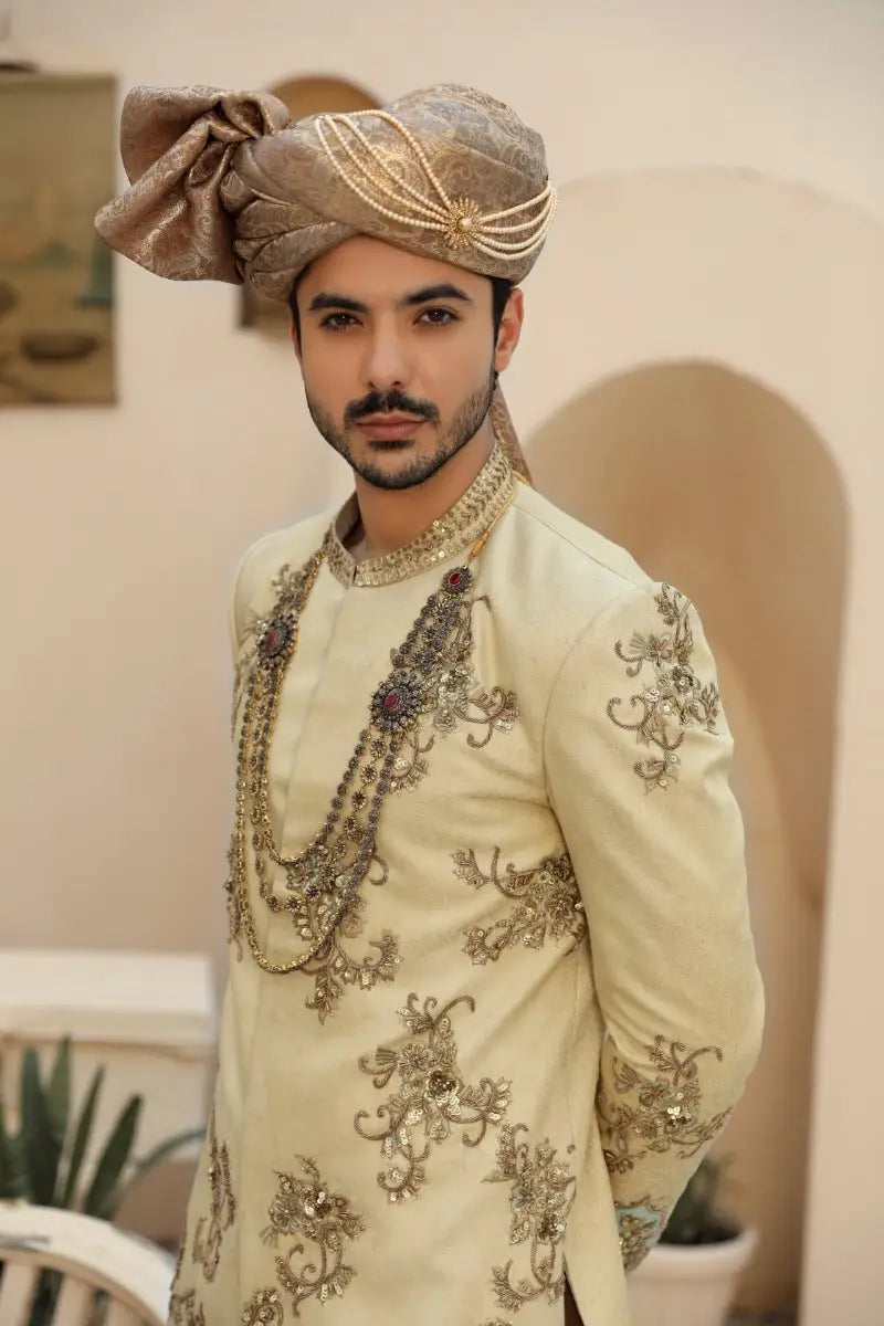Beige embroidered sahar sherwani with antique gold thread and embellishments paired with matching turban from raqeeb se collection prince coat