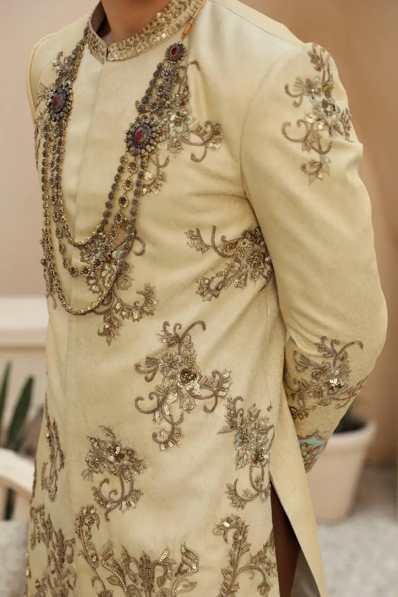 Cream-colored sahar sherwani with gold threadwork and red gemstones from raqeeb se collection by ahsan tariq prince coat