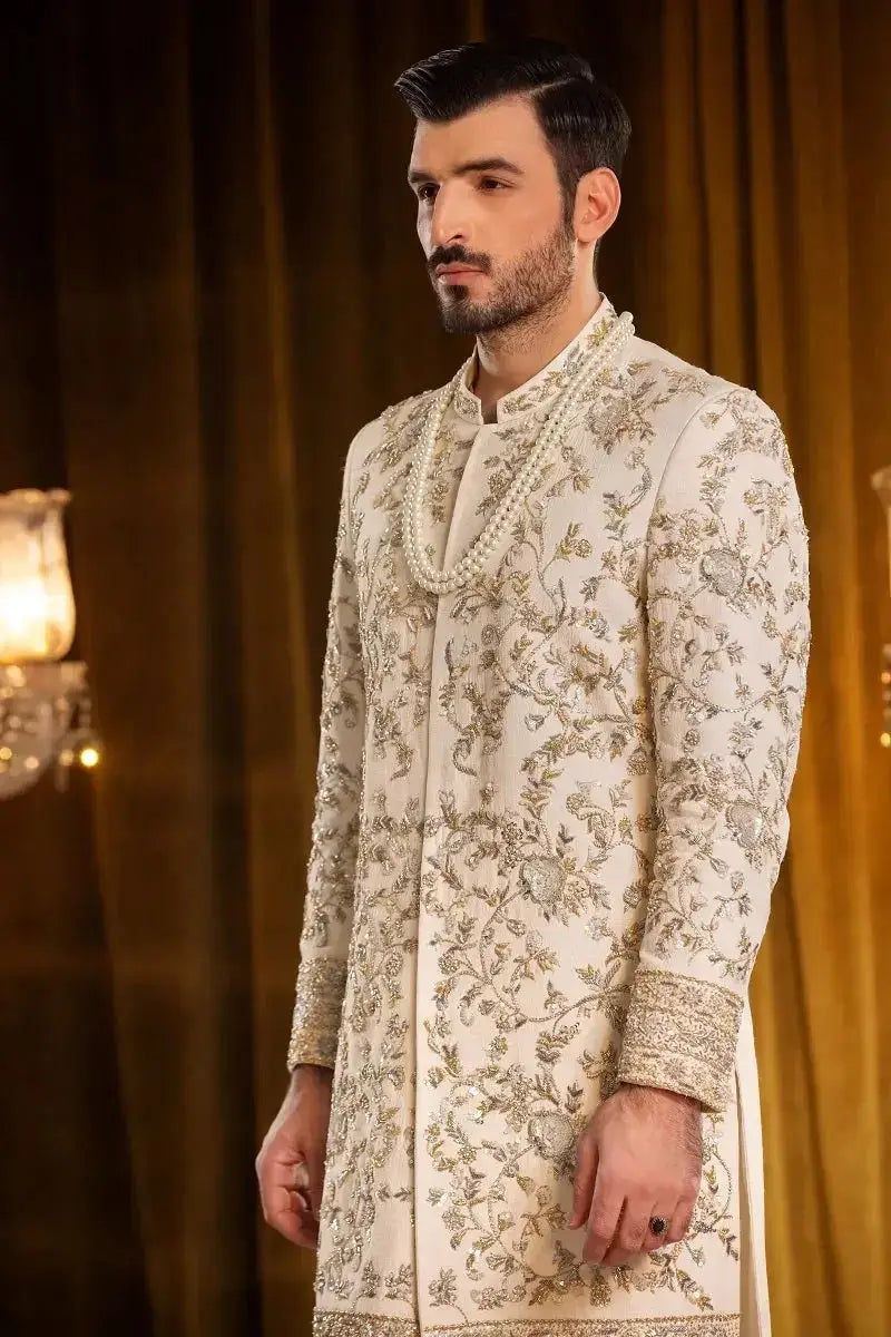 Saleem cream-colored sherwani with intricate gold embroidery and a pearl necklace showcasing traditional elegance