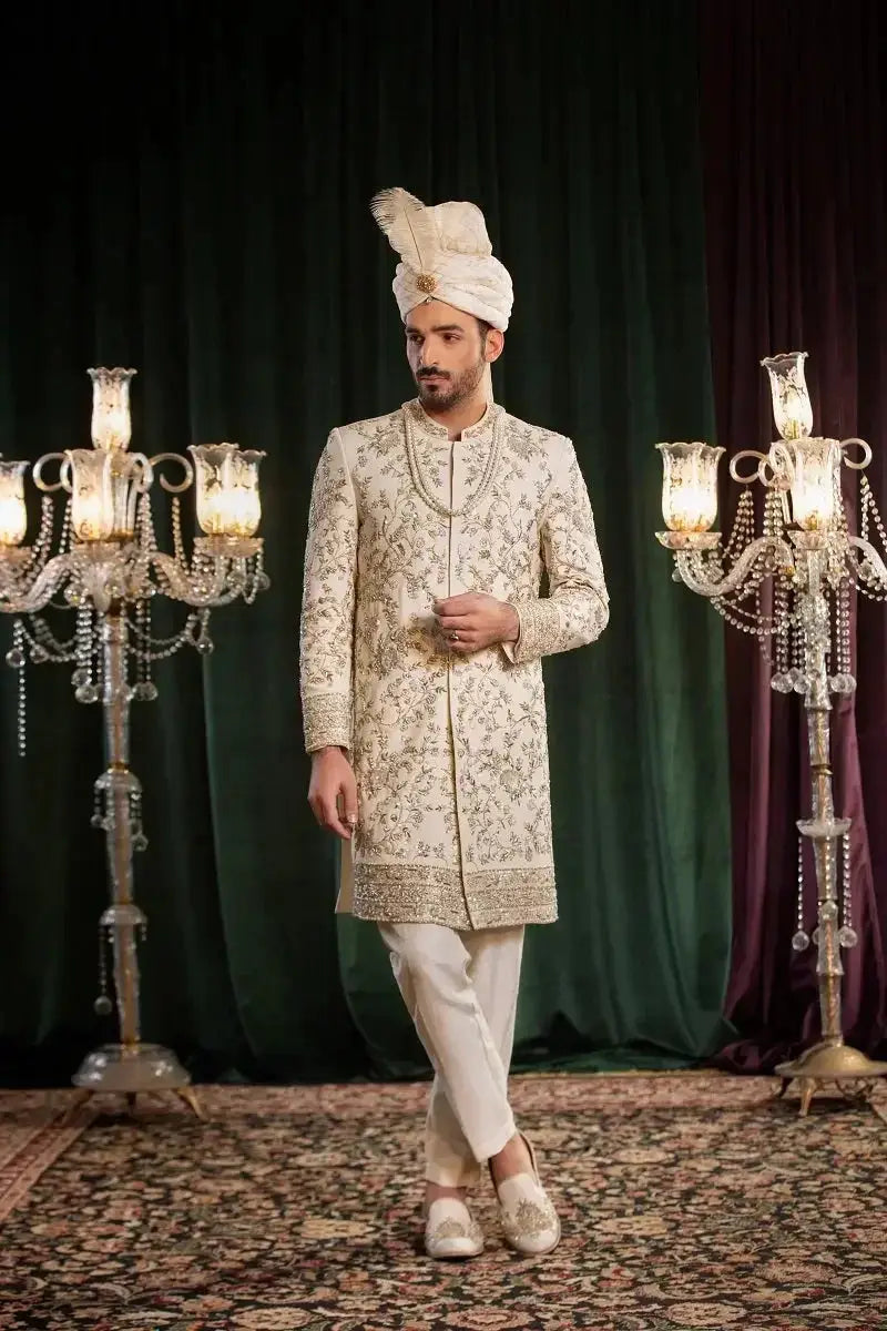 A man wearing saleem cream sherwani with intricate gold thread embroidery and a matching turban