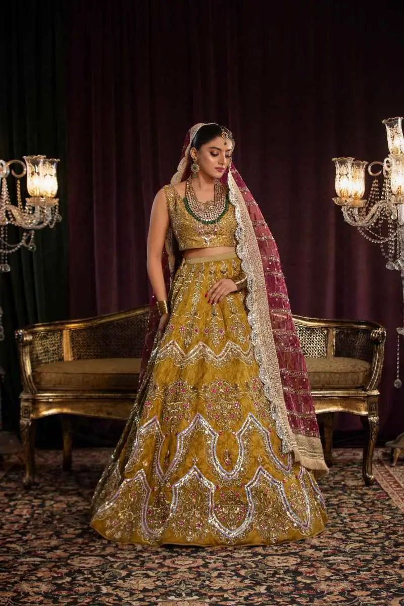 A woman wears a sila lehenga featuring architectural chevron silver embroidery in gold with a maroon lace-edged dupatta